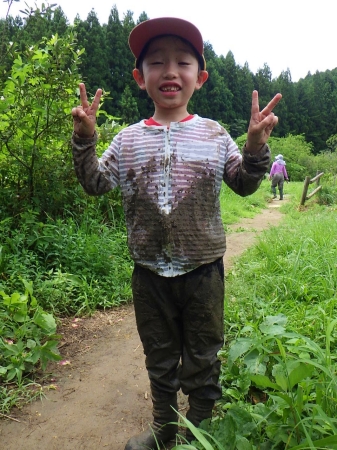 田んぼ前でピースする少年